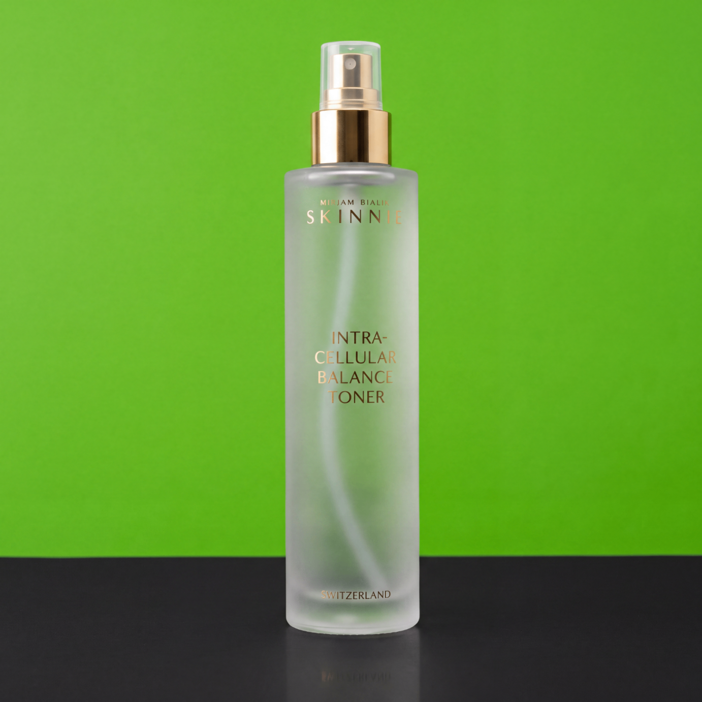 Satinierte Skinnie-Toner-Flasche mit goldenem Siebdruck vor grünem Hintergrund